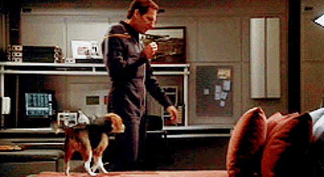 a man standing next to a dog in a living room with a red couch