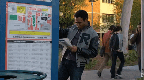 a man wearing a jacket with the letter r on it is reading a newspaper