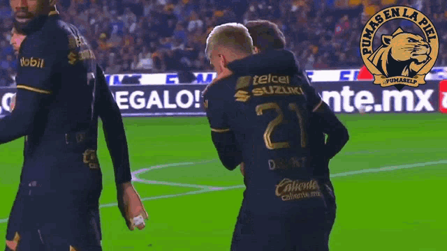 a soccer player wearing a number 21 jersey is hugging another player