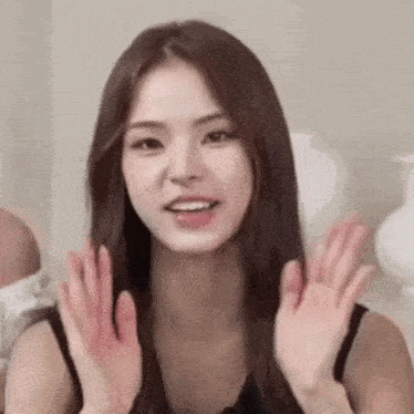 a close up of a woman 's face with her hands up .