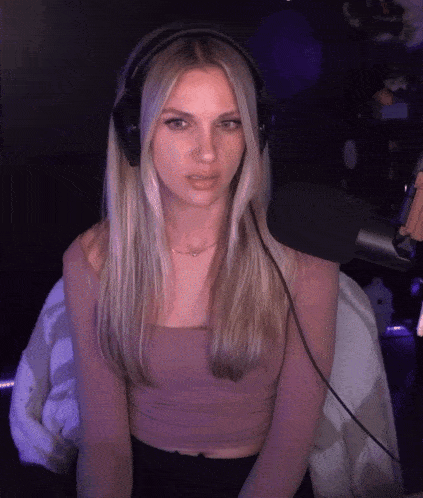 a woman wearing headphones is sitting in front of a microphone looking at the camera