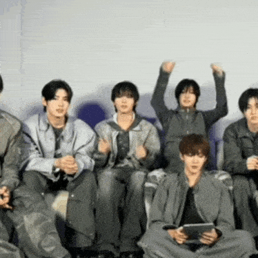 a group of young men are sitting on a couch with their hands in the air