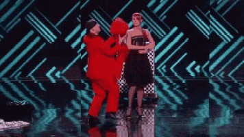 a man in a red suit is standing next to a woman in a black dress