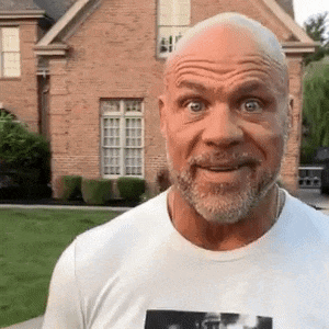 a bald man with a beard is wearing a white t-shirt and making a funny face .