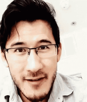 a man wearing glasses and a beard is smiling for the camera .