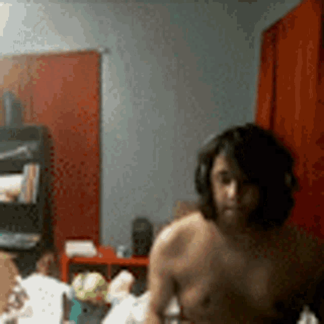 a shirtless man wearing headphones stands in a room