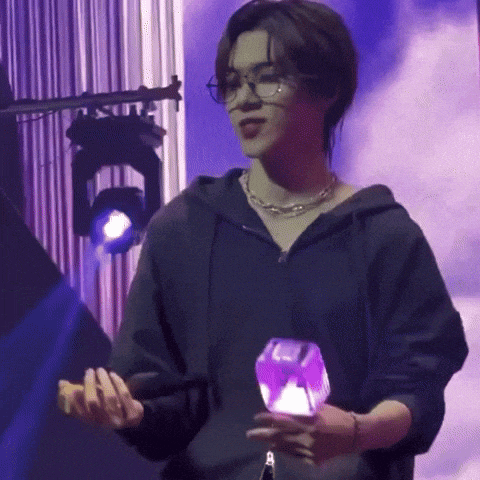 a man wearing glasses and a black hoodie is holding a purple object