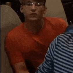 a man in a red shirt and glasses is dancing in a room .