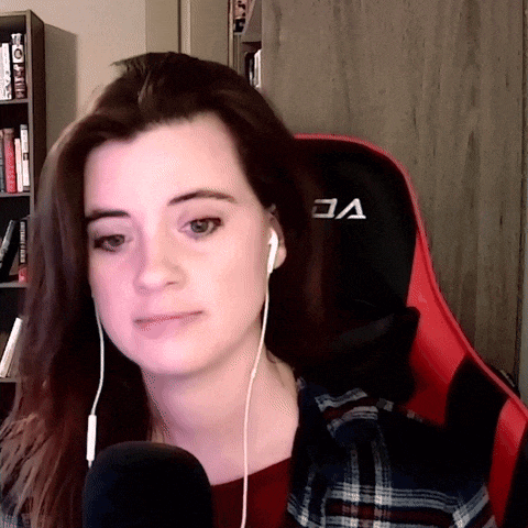 a woman wearing headphones sits in a red and black chair with the letter v on the back