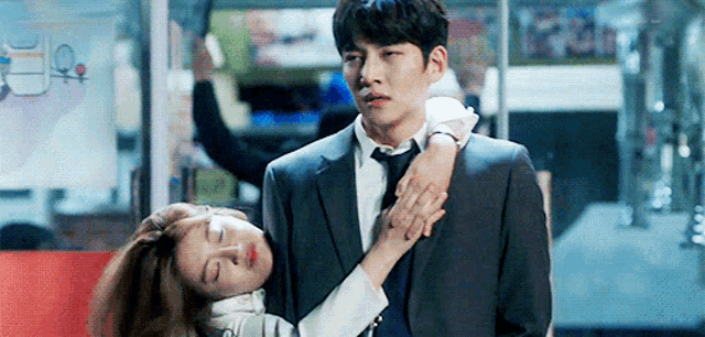 a man in a suit and tie is hugging a woman who is laying on his lap .