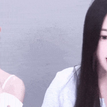 a close up of a woman 's face with long black hair and a white shirt .