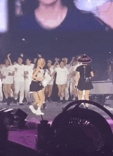 a group of people are dancing on a stage and one of them is wearing a sombrero that says ' mexico ' on it