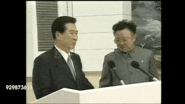 two men are standing at a podium with the number 929873618 on the bottom