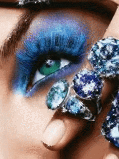 a close up of a woman 's face with blue eye makeup and rings