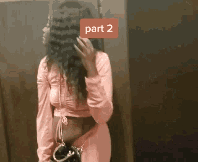 a woman in a pink dress is standing in front of a door with a red sticker that says part 2 on it