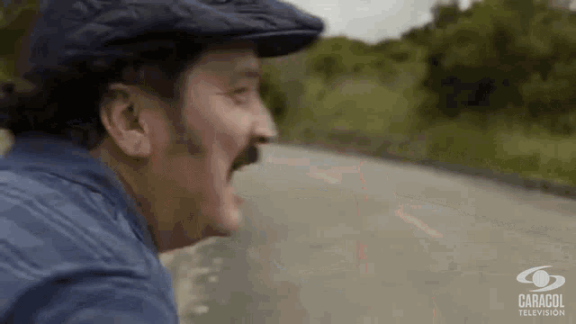 a man wearing a hat and a blue shirt is screaming on a road .