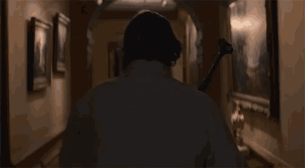 a man is walking down a hallway holding a large hammer .