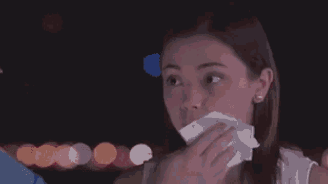 a woman is blowing her nose with a tissue in a blurry photo .