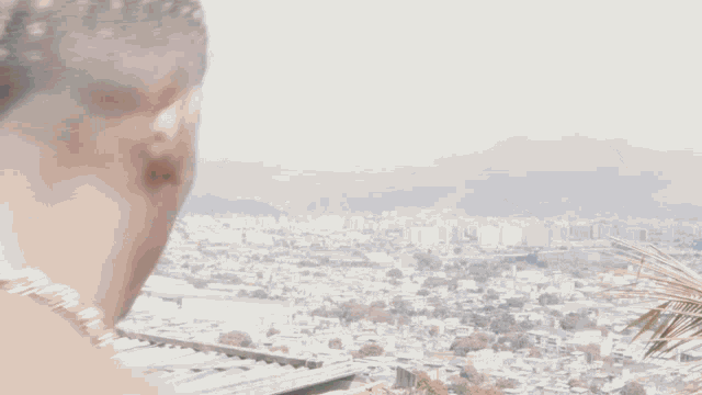 a man without a shirt is looking at a city with mountains in the background