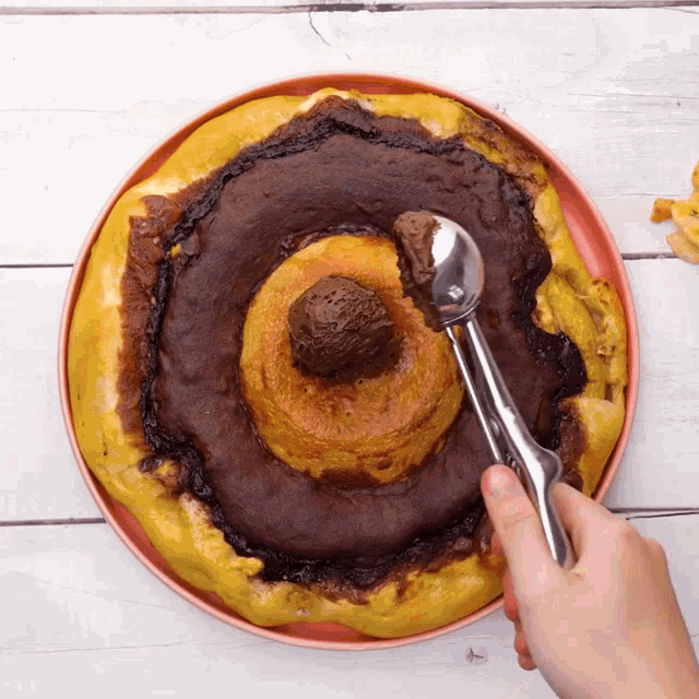 a person is scooping ice cream out of a cake on a pink plate