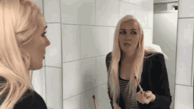 a woman is looking at herself in a mirror