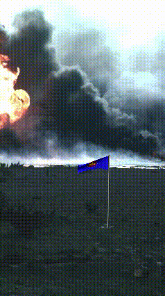 a blue and yellow flag is flying in front of a large fire