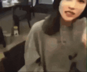 a woman is taking a selfie in a room with a table and chairs .