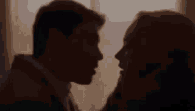 a man and a woman are kissing in a dark room .