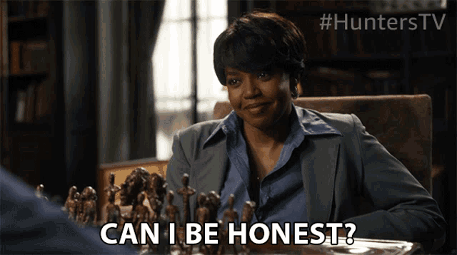a woman is sitting at a table with a chess board and says can i be honest