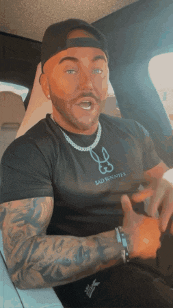 a man wearing a bad minnies t-shirt is sitting in a car