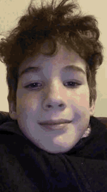 a young boy with curly hair is making a funny face .