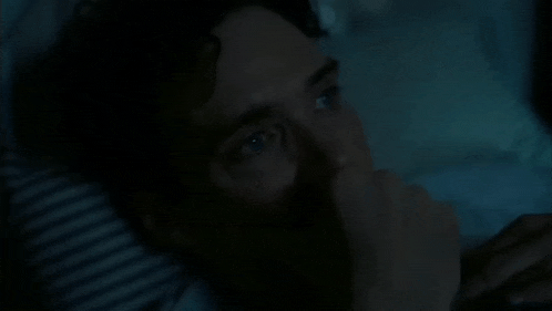a man is laying on a bed with his eyes closed and his mouth open .