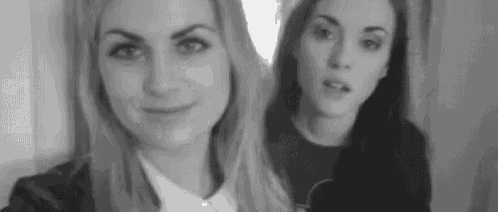 two women are standing next to each other in a black and white photo and smiling .