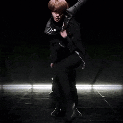 two men are dancing in a dark room and one has a badge on his jacket that says ' police '