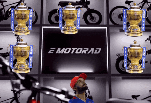 a man in a red hat stands in front of a display of trophies and a motorad logo