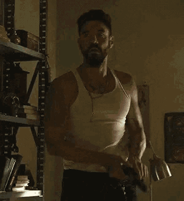 a man with a tattoo on his arm is holding a gun in his hand .