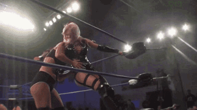 two women are wrestling in a ring and one is wearing black shorts