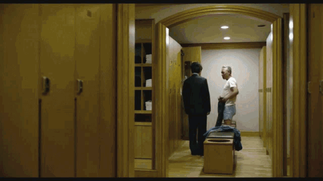 a man in a suit and a man in a white shirt standing in a locker room