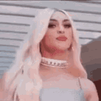 a woman with blonde hair is pointing at the camera with her tongue out .