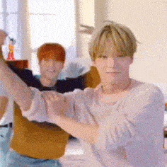a man in a pink shirt is dancing with another man in a yellow shirt