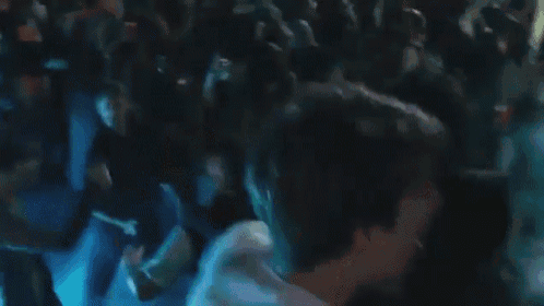 a man in a white shirt is standing in front of a crowd of people dancing .