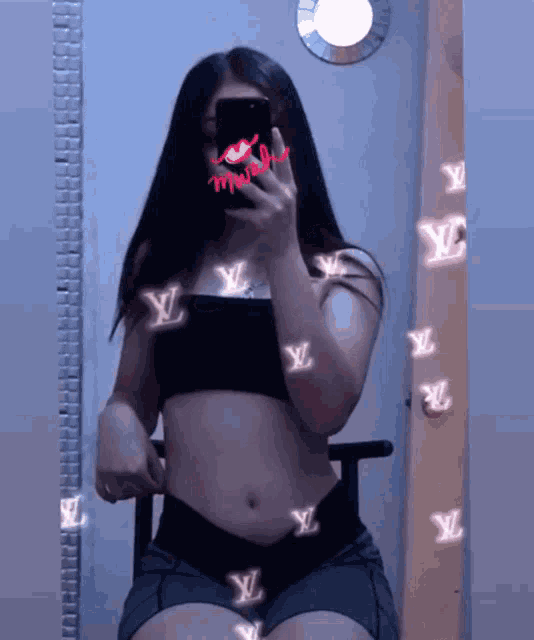 a woman taking a picture of herself in front of a mirror with a louis vuitton logo on her face