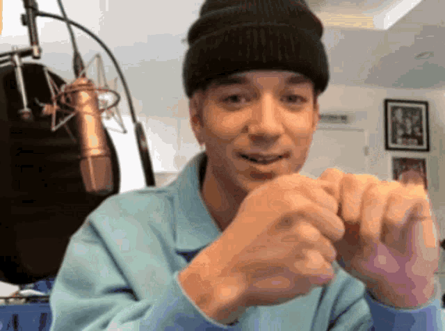 a man wearing a black beanie and a blue shirt is smiling