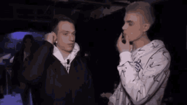 two young men are talking to each other in a dark room