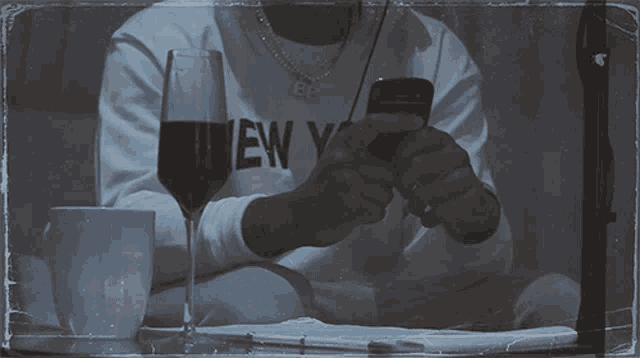 a person wearing a new york sweatshirt looks at their cell phone