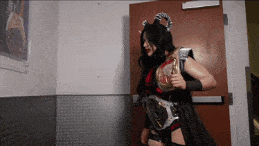a woman in a devil costume is holding a belt that says ' intercontinental ' on it
