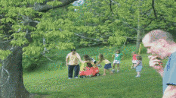 a blurred image of people playing in a park with trees in the background