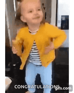 a little girl is wearing a yellow jacket and holding a glass of water .