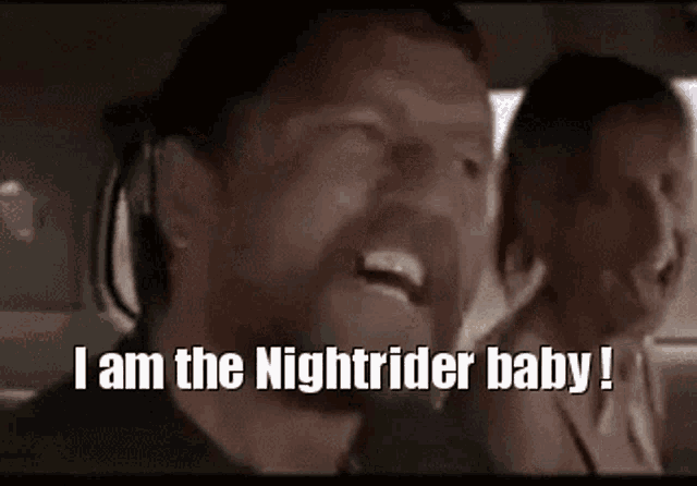a man with a beard is screaming in a car with the words i am the nightrider baby .