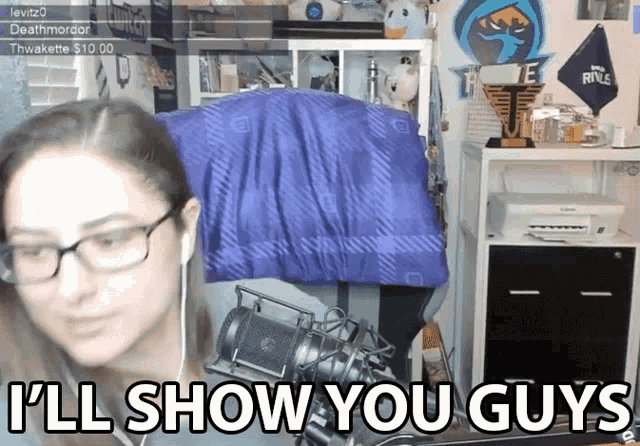 a woman wearing glasses says i 'll show you guys in front of a microphone
